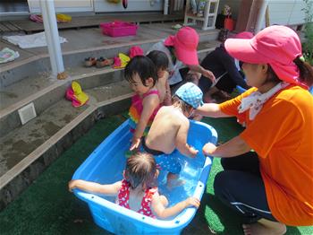 小さいプールで子供が水遊びをしている写真