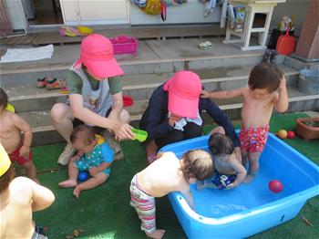 小さいプールで子どもが水遊びをしている写真