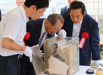 タイムカプセルの中身を確認する当時の担当職員(中央)
