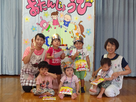 ステージの上に座っている子どもと大人