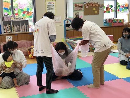 シフォン布のくるまれて、ママの腕の中に抱っこされるようす