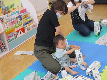 親子で新聞紙を牛乳パックに詰めている様子