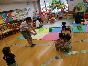 段ボール製の車に2人の子をのせて引っ張るパパ