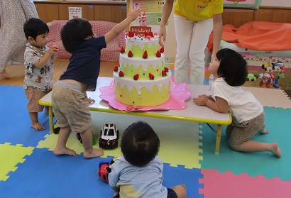 誕生ケーキに手を伸ばす子どもたち