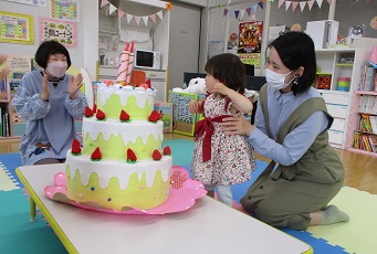 誕生ケーキをかこんで歌っている様子