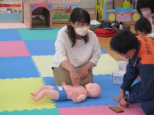 指導を受けながら胸部圧迫の実践をするママ