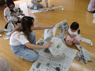 新聞紙を破って遊ぶ親子のようす