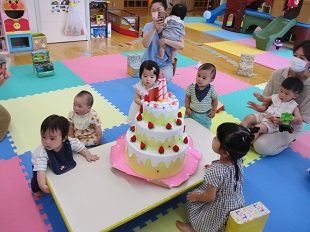 大きな誕生日ケーキに集まっているお友だちのようす