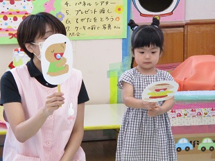 スタッフの隣で子どものカードを持って立つ女の子