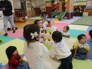 誕生日ケーキに集まっている子どもたち