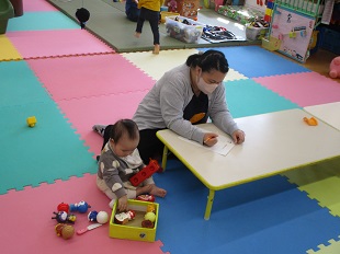 自由に思いを書いているママと、となりで安心して遊んでいる子ども