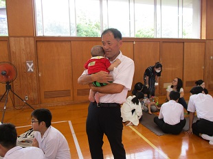 赤ちゃんを抱っこしている校長先生